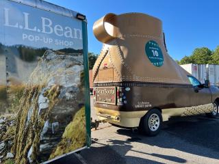 the L.L. Bean "bootmobile" in a parking lot next to an L.L. Bean advertisement