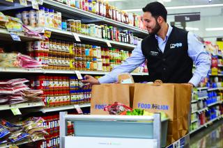 photo illustration: a food lion employees stocks brown paper bags with groceries
