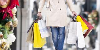 A woman holds shopping bags.