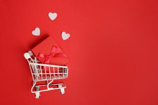 Valentine's Day graphic with hearts floating from a shopping cart on a red background.