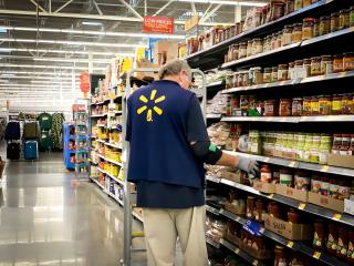 A Walmart employee stands next to a store shelf.