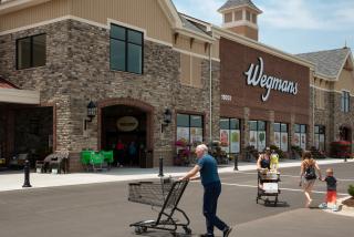 Shoppers enter and exit a Wegmans store.