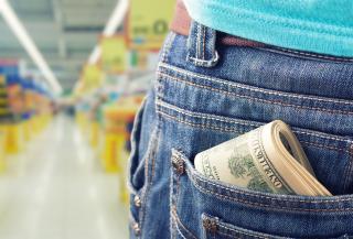 A person in a grocery store has cash in their pocket.