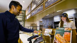 A customer waves his palm above an Amazon One device in a Panera Bread.