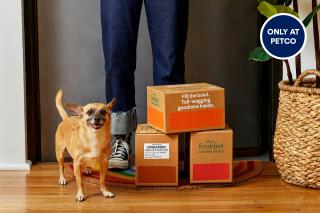 A dog stands next to three boxes in an advertisement for Petco's collaboration with Freshpet.