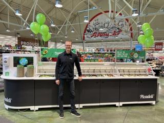 A man stands in front of the smart salad bar.