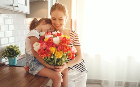 a person standing next to a vase of flowers on a table