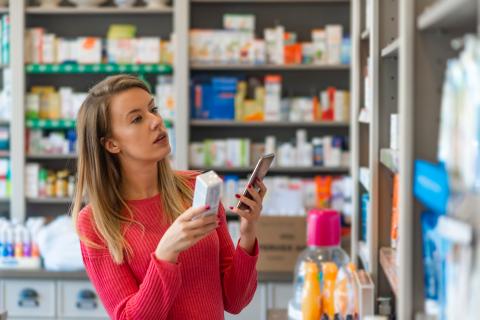 a woman holding a phone in front of a store