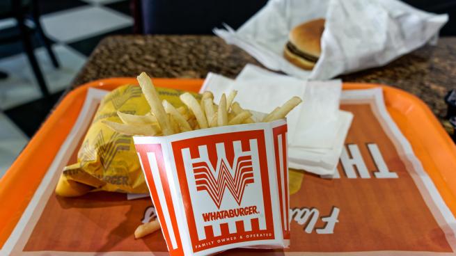 A photo of a orange Whataburger tray with a burger and french fries.