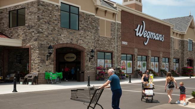 Shoppers enter and exit a Wegmans store.