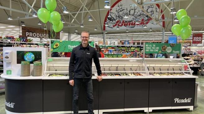 A man stands in front of the smart salad bar.