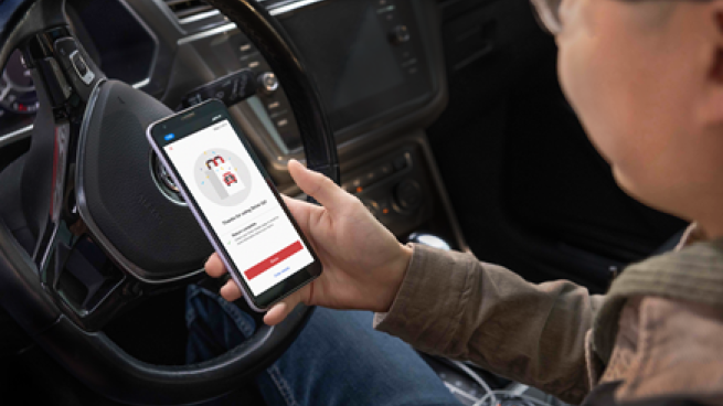 A person in a car holds a phone with Target's drive up return interface.
