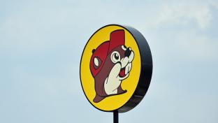 A sign of the Buc-ee's logo with a blue sky in the background.